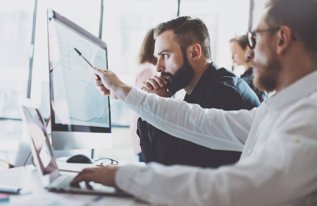 Image depicting a finance trade manager showing reports on a screen to a young business crew, highlighting a collaborative working process