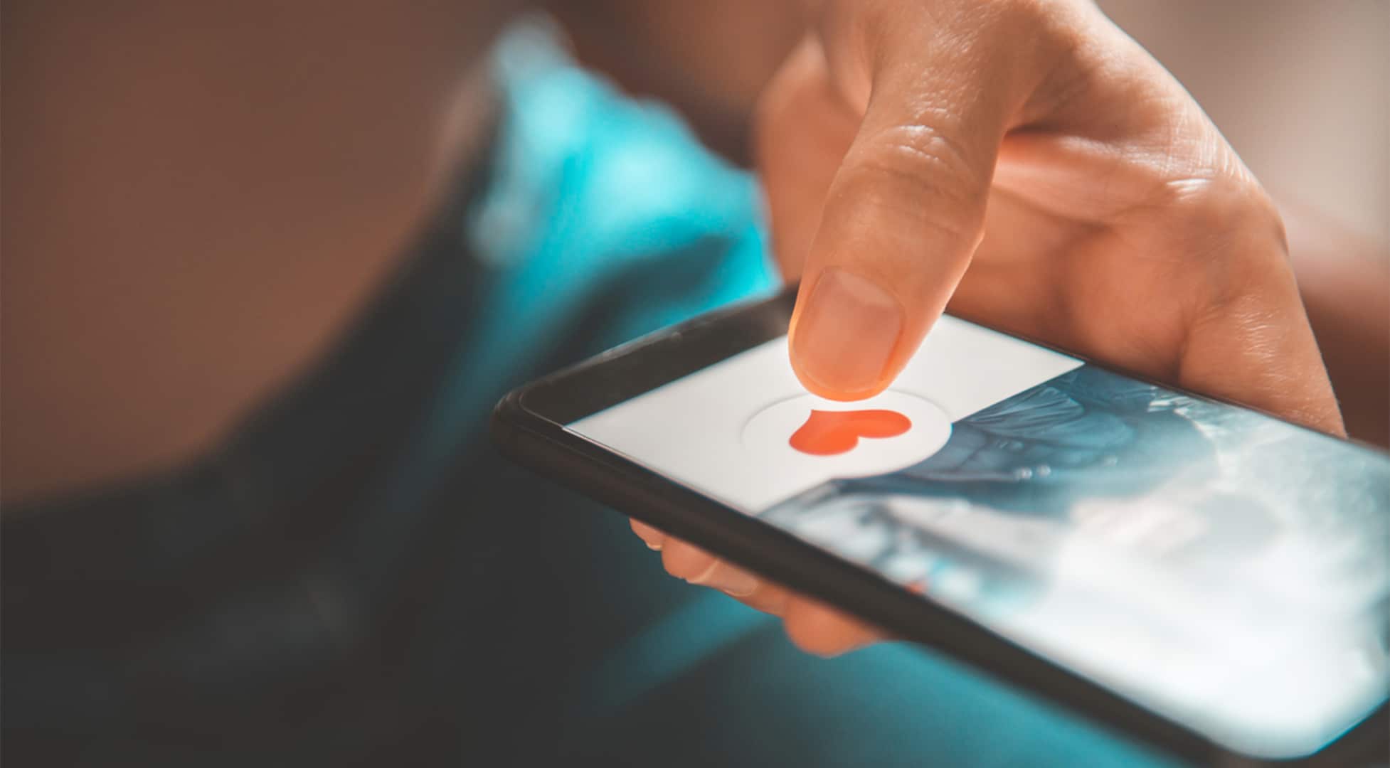 Finger pusing heart icon on screen in mobile